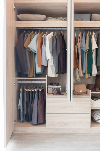 Clothes hanging on rails in wooden wardrobe — Stock Photo, Image