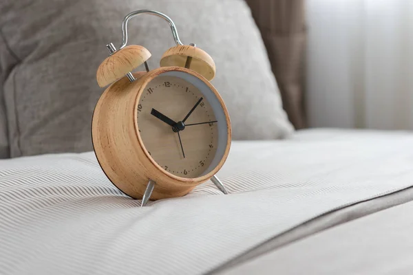 Wooden modern alarm clock on bed — Stock Photo, Image