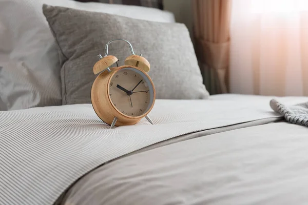 Wooden modern alarm clock on bed — Stock Photo, Image