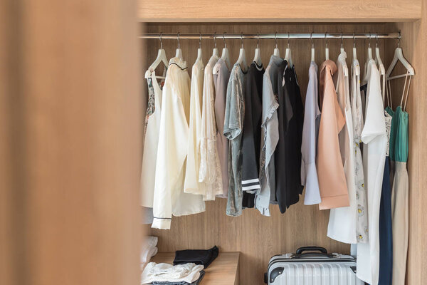 деревянный шкаф с одеждой, висящей на перилах
