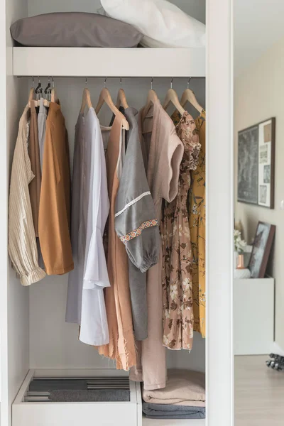 wooden wardrobe with clothes hanging on rail