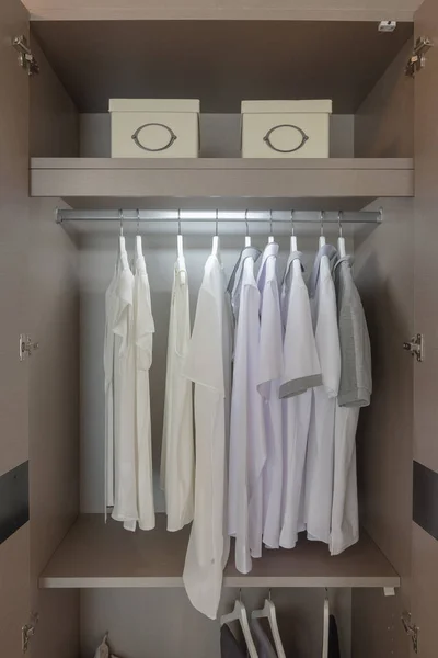 Одежда висит на поручне в деревянном шкафу — стоковое фото