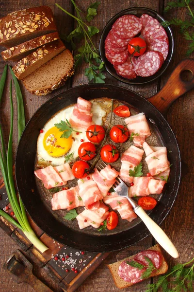 Жареные яйца, бекон, копченое мясо, колбаса, овощи и травы, — стоковое фото
