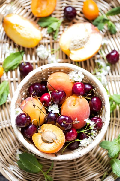 Свежие фруктовые абрикосы и вишни в плетеной корзине — стоковое фото