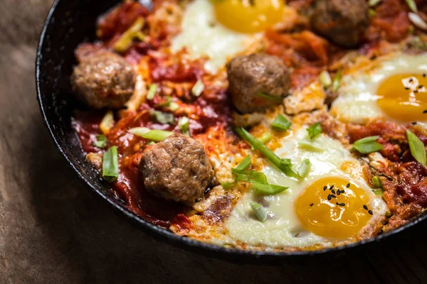 shakshuka, yumurta, domates ve yeşillik ahşap arka plan üzerinde köfteyle İsrail çanak