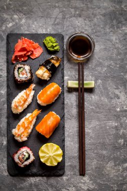 suşi ve suşi rulo, suşi nigiri koyu arka plan, hardal wasabi ve zencefil taş plaka üzerinde