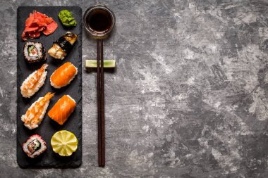suşi ve suşi rulo, suşi nigiri koyu arka plan, hardal wasabi ve zencefil taş plaka üzerinde