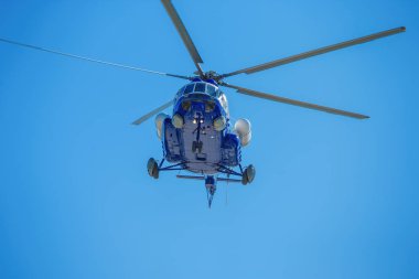 Mavi gökyüzünde uçan helikopter.