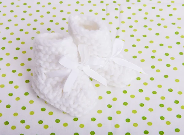 Вязаные детские носки на фоне тканей — стоковое фото