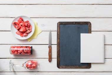 Kara tahta ve karpuz ile masa üstünde defter.