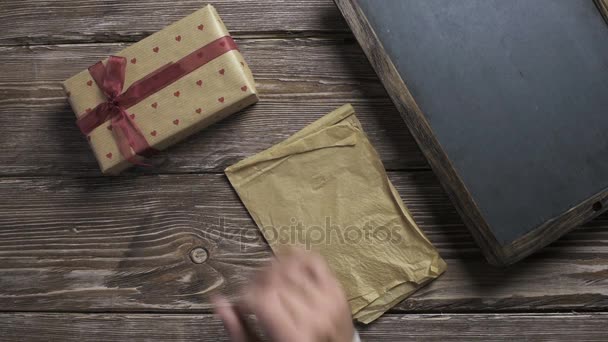 Man zet geschenkdozen één voor één naar houten bureaublad — Stockvideo