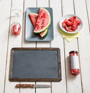 Kara tahta ve karpuz ile masa üstünde defter.