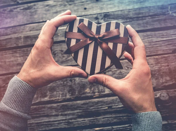 Caja de regalo en forma de corazón en las manos del hombre . —  Fotos de Stock