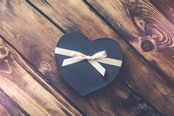 Black heart shaped gift box on old wood — Stock Photo, Image