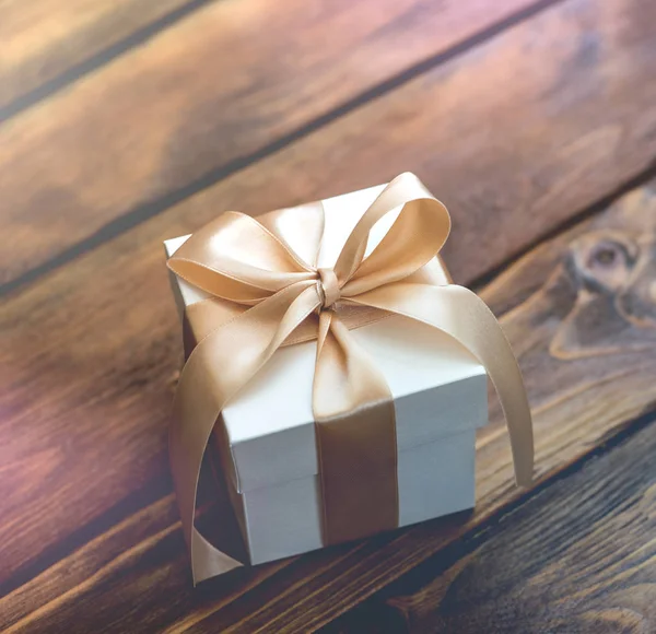 Подарункова коробка з золотою стрічкою на дереві — стокове фото