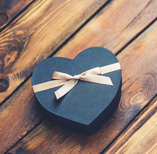 Caja de regalo en forma de corazón negro en madera vieja — Foto de Stock