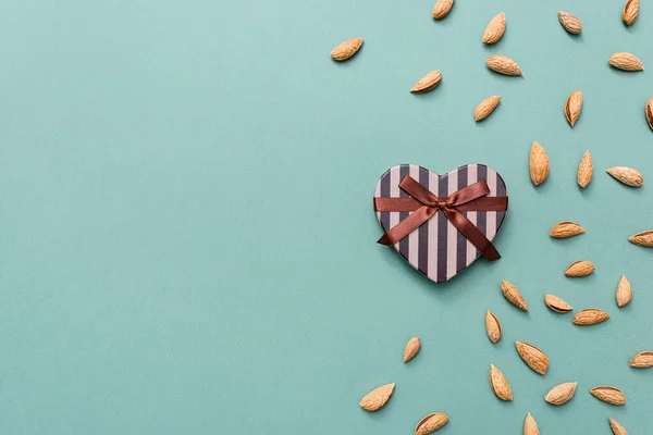 Caja de regalo en forma de corazón entre almendras — Foto de Stock