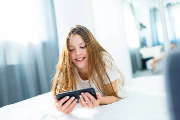Ragazza adolescente sorridente con uno smartphone in mano - apprendimento a distanza — Foto Stock