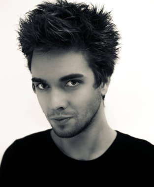 Genç yakışıklı bir adamın portresi dağınık saçlı, sakallı ve siyah gömlekli beyaz bir arka planda hafifçe çevrilmiş bir adam..