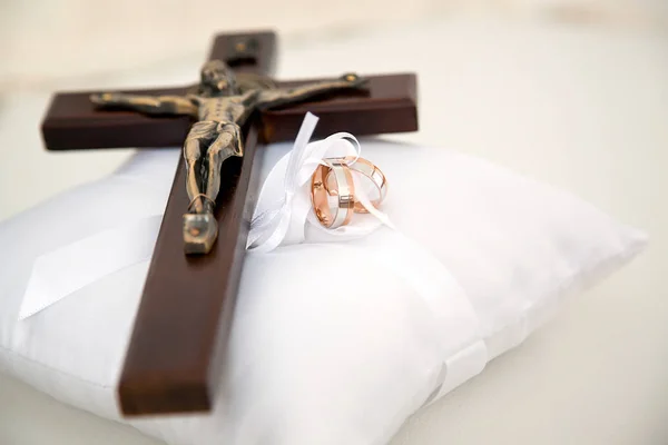 Cruz cristiana y anillos de boda en cojín blanco — Foto de Stock