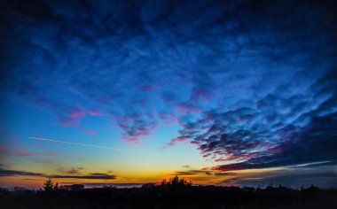 Günbatımı gökyüzü panorama uçak, silhouette ağaçlar ve köy evleri ile.