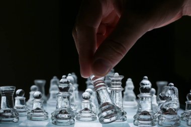 Close-up view on the transparent glass chess board with male hand clipart