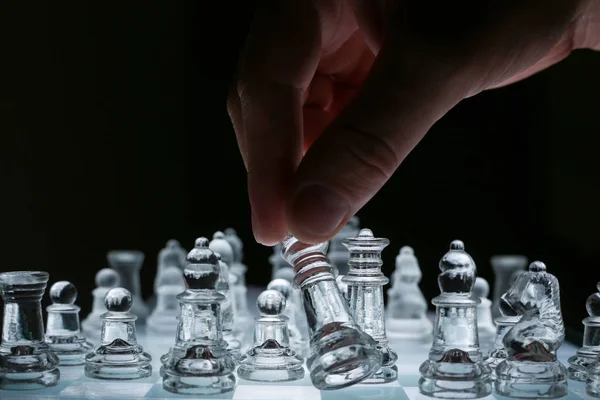 Крупный план на прозрачной стеклянной шахматной доске с мужской рукой Стоковое Изображение