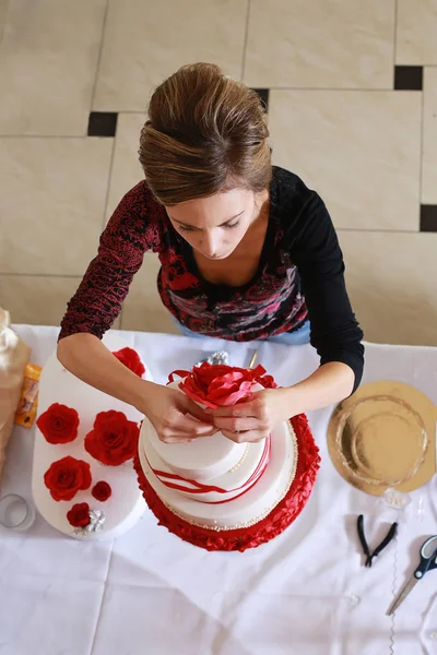 Confectioner decorating a wedding cake with marzipan flowers