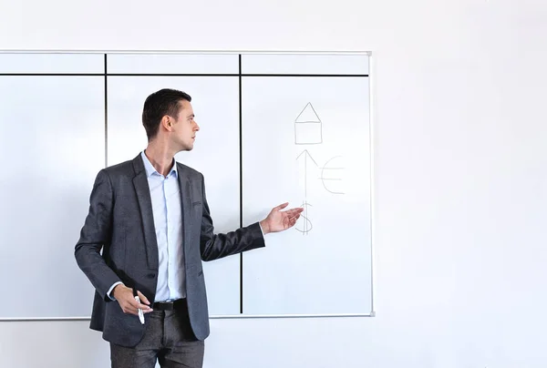 Homme adulte en costume debout devant un tableau blanc — Photo