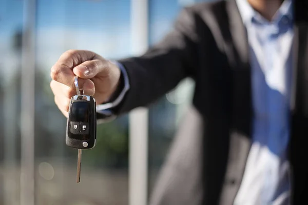 Взрослый дилер раздает ключи от машины, фото крупным планом на открытом воздухе Стоковая Картинка
