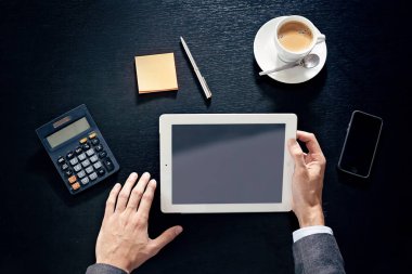 tablet, telefon, hesap makinesi, bir siyah tahta masada adam eller iş görüntülemek yukarıdan
