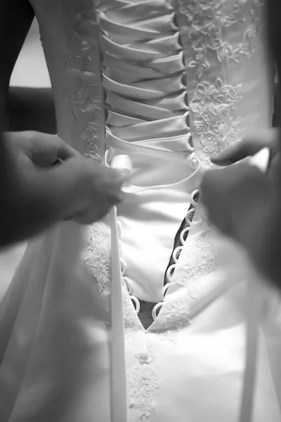 hands tying a wedding dress, close-up of brides back in white wedding dress, black and white photo