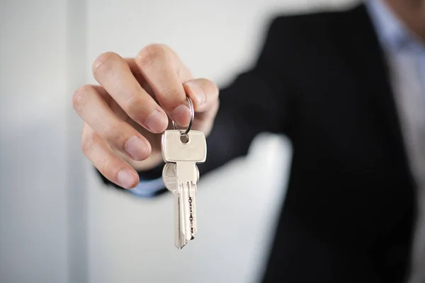 Взрослый мужчина в костюме дает ключ от дома, крупным планом фотографию руки и ключи Стоковое Изображение