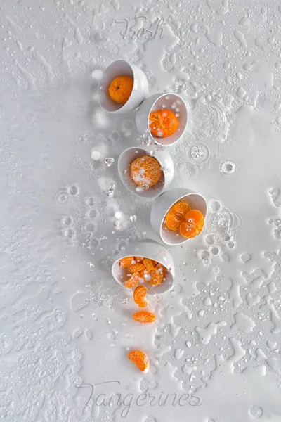 Cinco cuencos blancos con mandarinas, salpicaduras de agua, fondo blanco, vista desde arriba — Foto de Stock