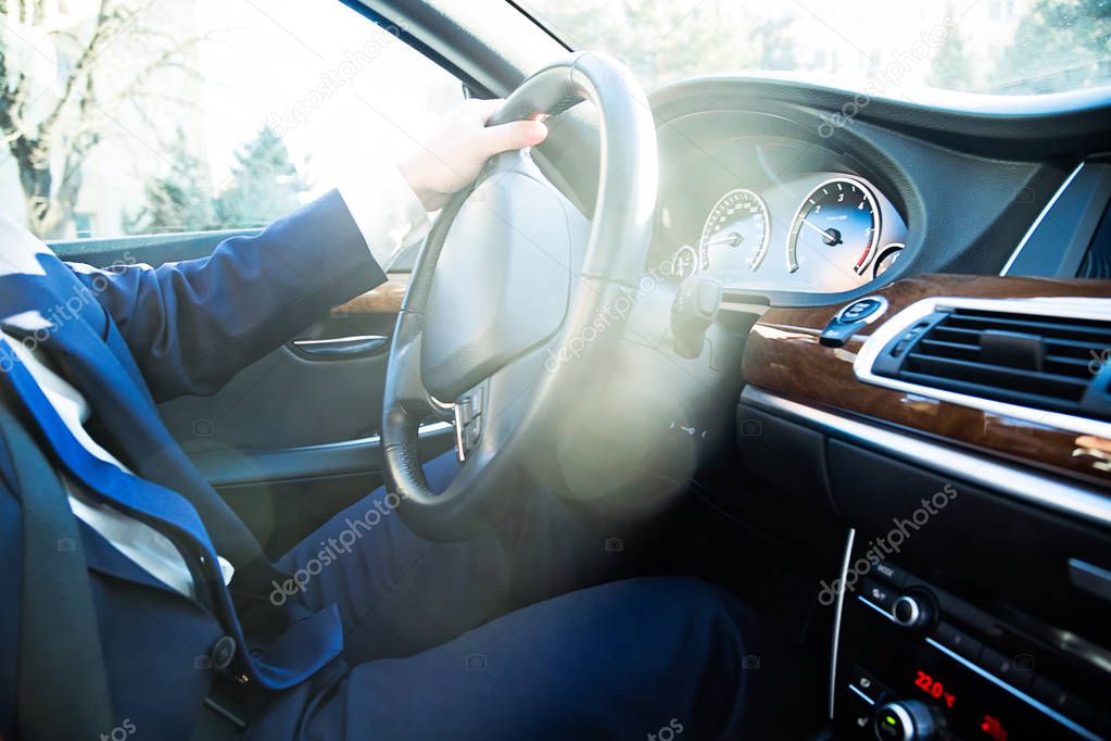 Close-up of driver sitting in the car behind the wheel, sunny day