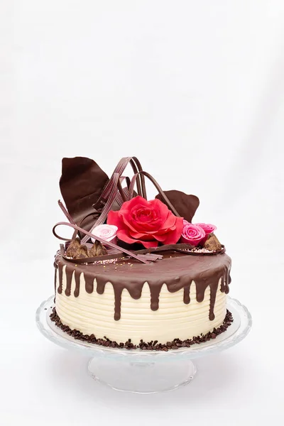 Рулон, один слой белого и коричневого шоколадного торта с красными и розовыми съедобными цветами марципана сверху Лицензионные Стоковые Изображения