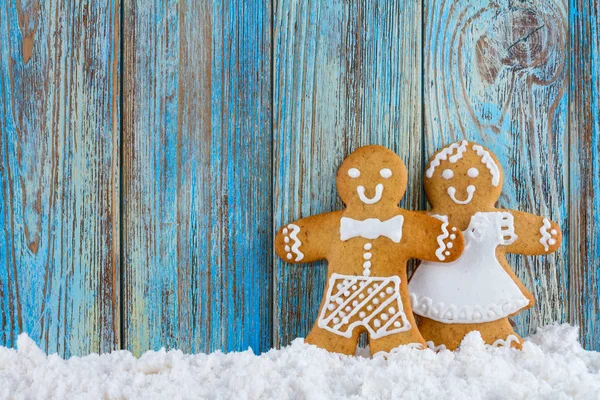 Gingerbread cookies, gingerbread men in the snow on blue wooden background, Christmas or New Year background, template greeting card