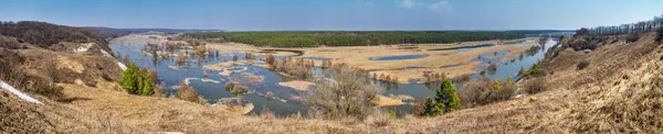 Spring landscape banner, panorama - spring flood in river valley of the Siverskyi (Seversky) Donets, the winding river over the meadows between hills and forests, border region of Ukraine near to Russia
