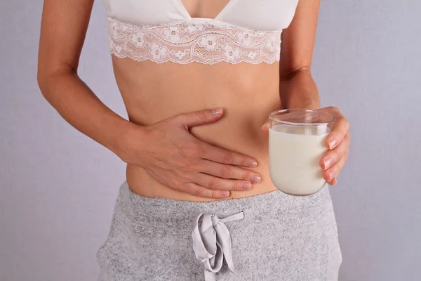 Mujer con dolor de estómago sosteniendo un vaso de leche. Lácteos Persona intolerante. Intolerancia a la lactosa, concepto de atención sanitaria . —  Fotos de Stock