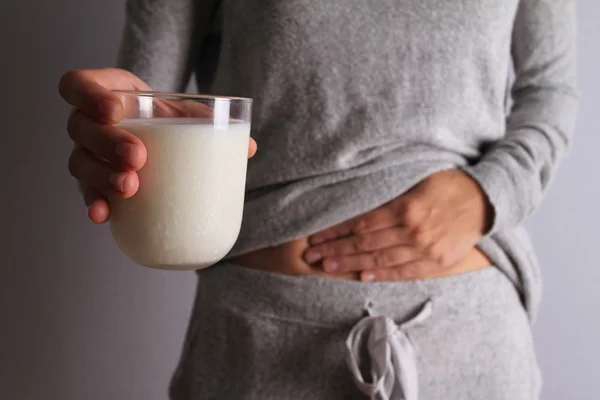 Mujer con dolor de estómago sosteniendo un vaso de leche. Lácteos Persona intolerante. Intolerancia a la lactosa, concepto de atención sanitaria . —  Fotos de Stock