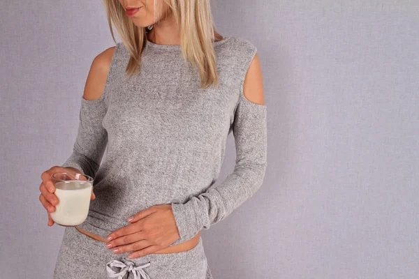 Donna con mal di stomaco con in mano un bicchiere di latte. Latticini Persona intollerante. Intolleranza al lattosio, concetto di assistenza sanitaria . — Foto Stock