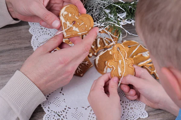 Nieuwjaar en gelukkige familie concept. Vader en kind maken maken kerstboom decoratie van peperkoek cookie close-up. Bakken met kinderen — Stockfoto