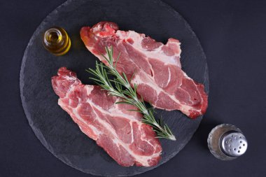 Çiğ domuz loin pirzola siyah arka plan, baharat, zeytin yağı. Arka plan, sağlıklı beslenme kavramı pişirme.