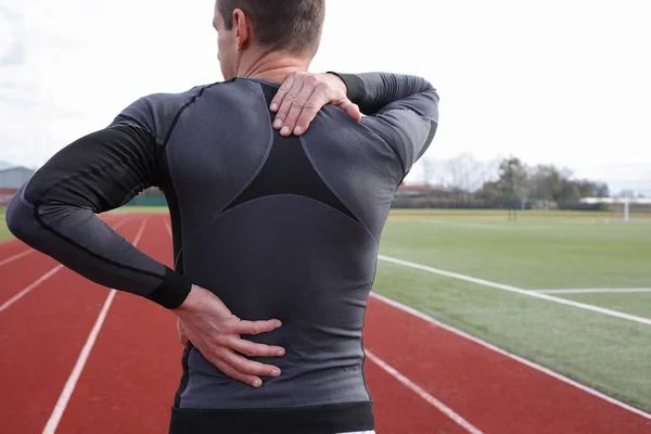 Hombre atlético con dolor de cuello y espalda. Lesiones por ejercicio deportivo . — Foto de Stock