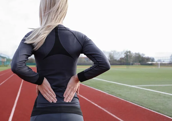 Dolor de espalda. Mujer atlética de fitness frotando los músculos de su espalda baja. Lesiones por ejercicio deportivo. — Foto de Stock