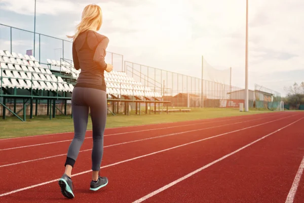 Mujer atlética en forma de fitness corriendo en el estadio. Deporte, jogging, concepto de estilo de vida saludable —  Fotos de Stock