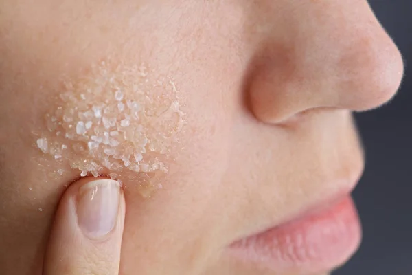 Mujer aplicando exfoliante facial casero de miel y sal marina. Concepto de cuidado de la piel — Foto de Stock