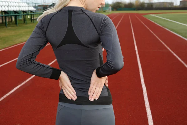 Dolor de espalda. Mujer atlética de fitness frotando los músculos de su espalda baja. Lesiones por ejercicio deportivo. — Foto de Stock