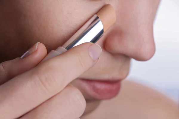 Mujer que aplica palo corrector o corrector, cubre círculos oscuros bajo los ojos. Belleza, maquillar concepto — Foto de Stock