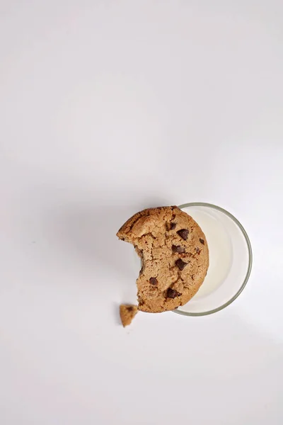 Chocolate Chip Cookie mit Biss gegessen und Glas Milch auf weißem Hintergrund, Minimalismus-Konzept. Neues Jahr und Weihnachten Urlaub Hintergrund, Kopierraum — Stockfoto